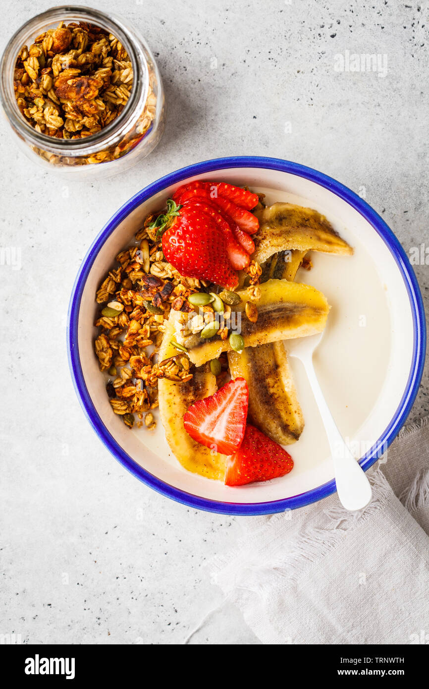 Hausgemachtes Müsli mit Erdbeeren und gebratenen Bananen in einer weißen Schüssel. Stockfoto