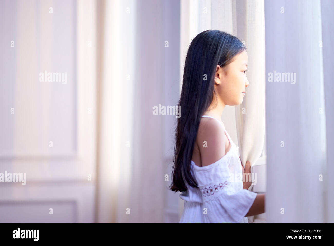9-jährige wenig asiatisches Mädchen stand vor der Fenster Stockfoto