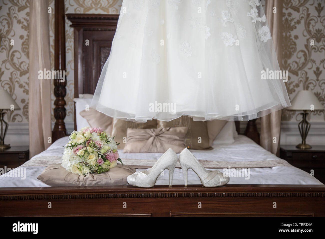Bräute Hochzeit Kleid Auflegen mit Schuhen und Blumen an der Vorderseite des Foto, warten Alle getragen zu werden von der Braut an ihrem Hochzeitstag. Stockfoto