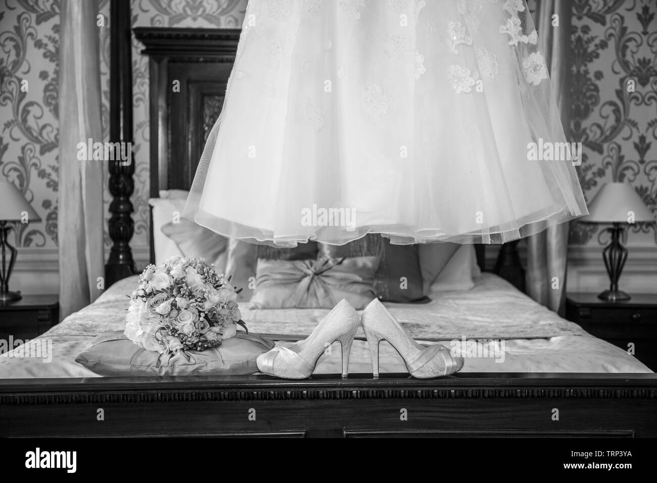 Bräute Hochzeit Kleid Auflegen mit Schuhen und Blumen an der Vorderseite des Foto, warten Alle getragen zu werden von der Braut an ihrem Hochzeitstag. Stockfoto