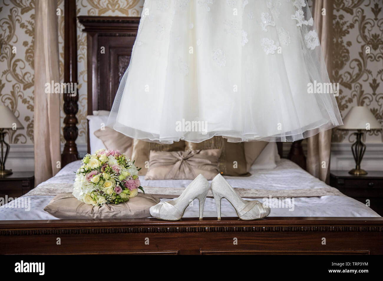 Bräute Hochzeit Kleid Auflegen mit Schuhen und Blumen an der Vorderseite des Foto, warten Alle getragen zu werden von der Braut an ihrem Hochzeitstag. Stockfoto
