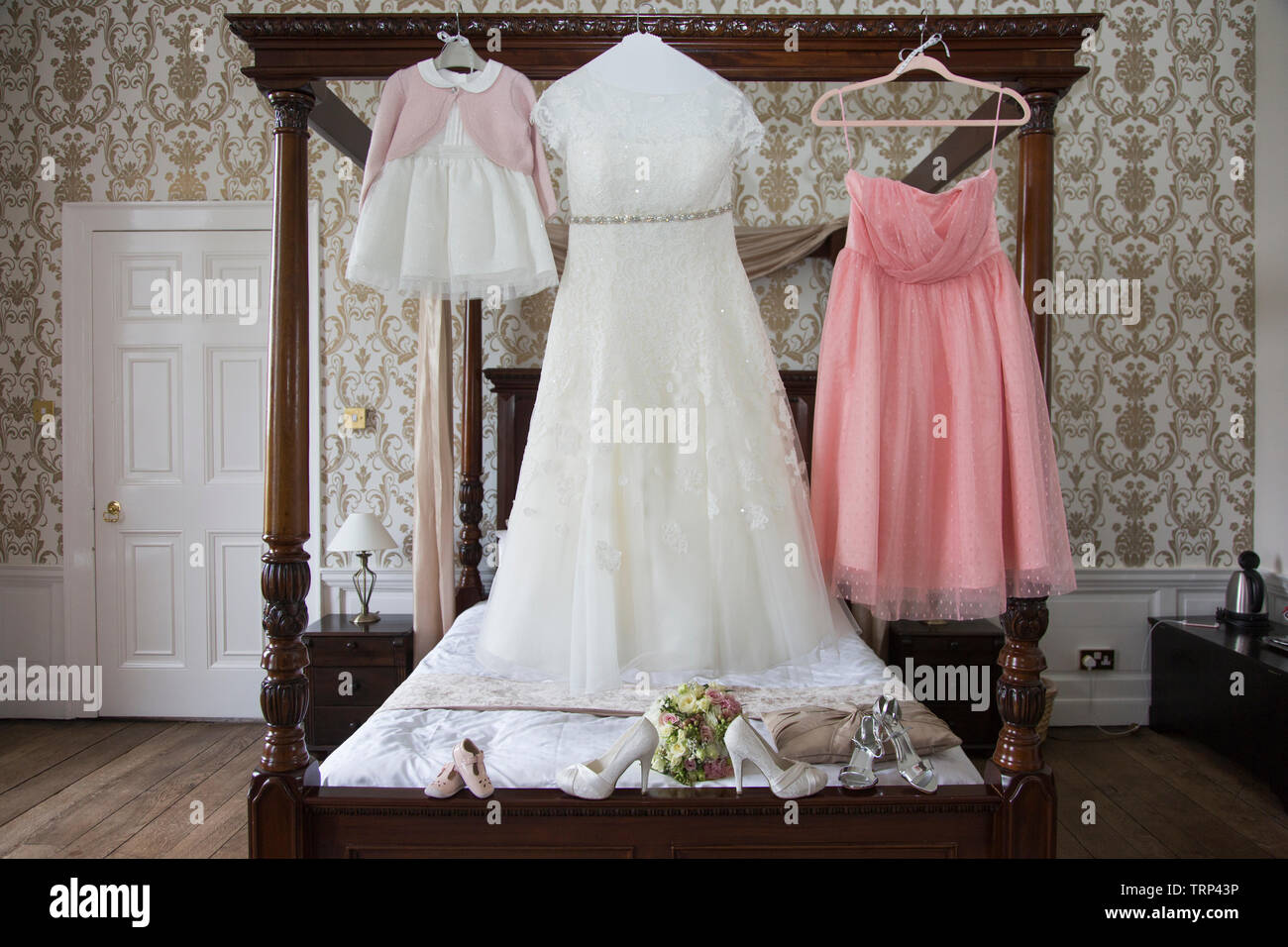 Bräute Hochzeit Kleid Auflegen mit Schuhen und Blumen an der Vorderseite des Foto, warten Alle getragen zu werden von der Braut an ihrem Hochzeitstag. Stockfoto