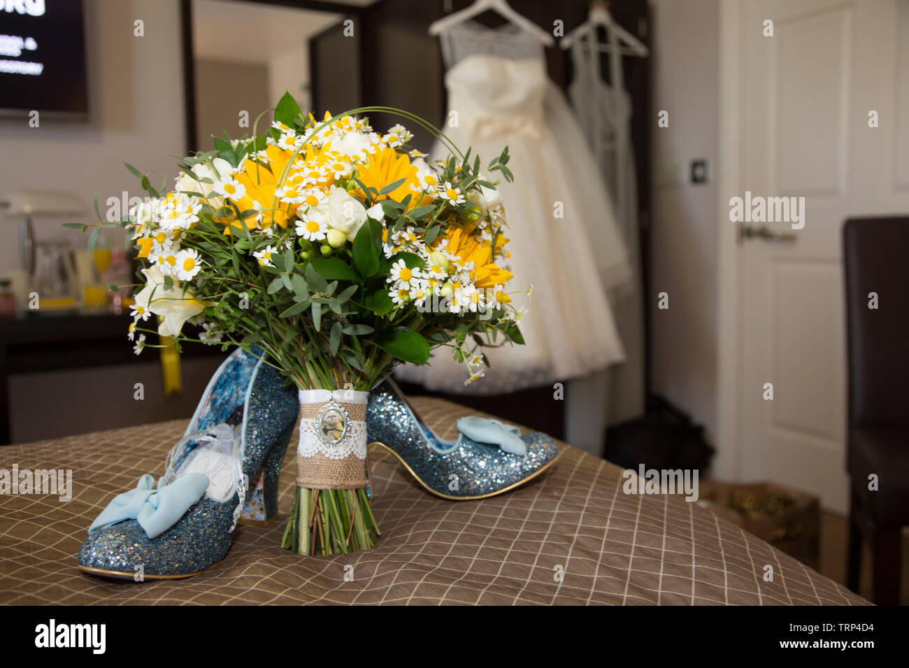 Bräute Hochzeit Kleid Auflegen mit Schuhen und Blumen an der Vorderseite des Foto, warten Alle getragen zu werden von der Braut an ihrem Hochzeitstag. Stockfoto