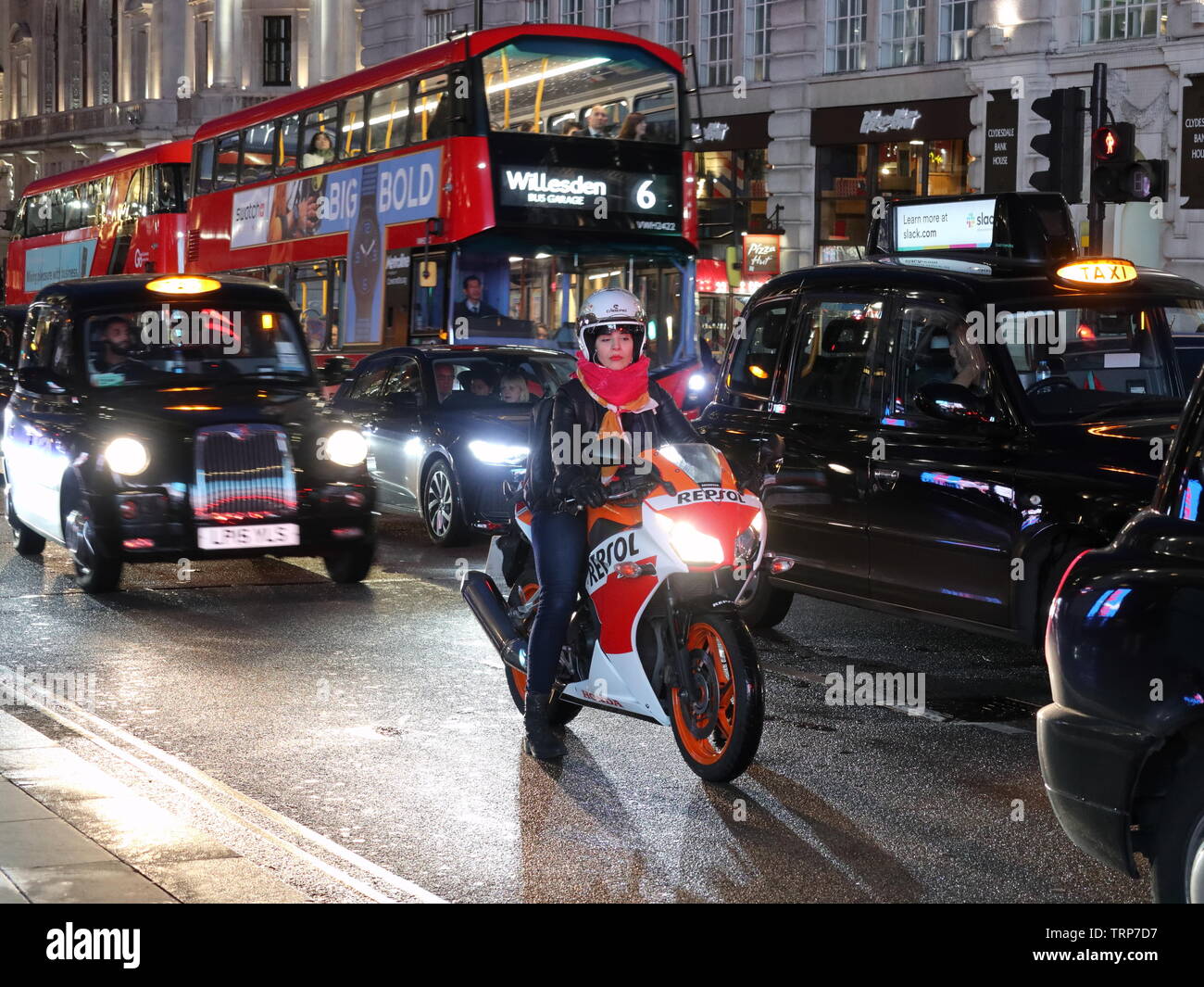 Frau Biker unter Verkehr in der Nacht, Piccadilly, London, England, Großbritannien Stockfoto