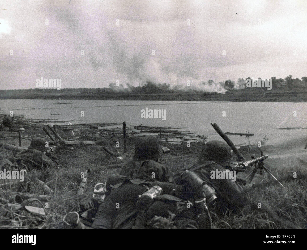 Waffen-SS in der Tarnung Kittel mit Licht MG 34 geben Feuerschutz für Deutsche Truppen an einem Fluss an der russischen Front 1941 Stockfoto