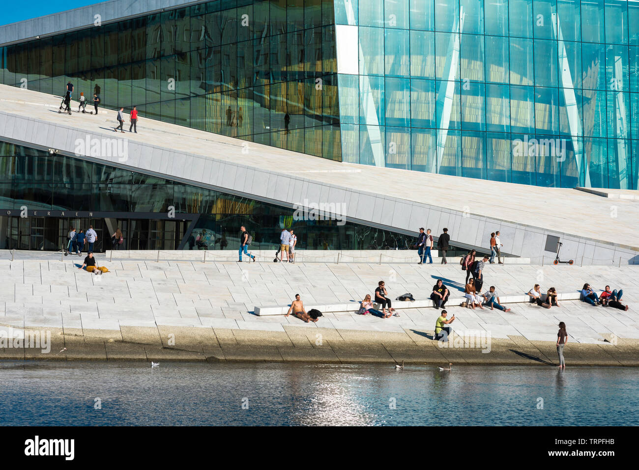 Oper Oslo, Blick aufs Wasser im Sommer von Menschen zum Sonnenbaden oder zu Fuß auf den weiten Zugang Rampe auf dem Dach der Oper Oslo. Stockfoto