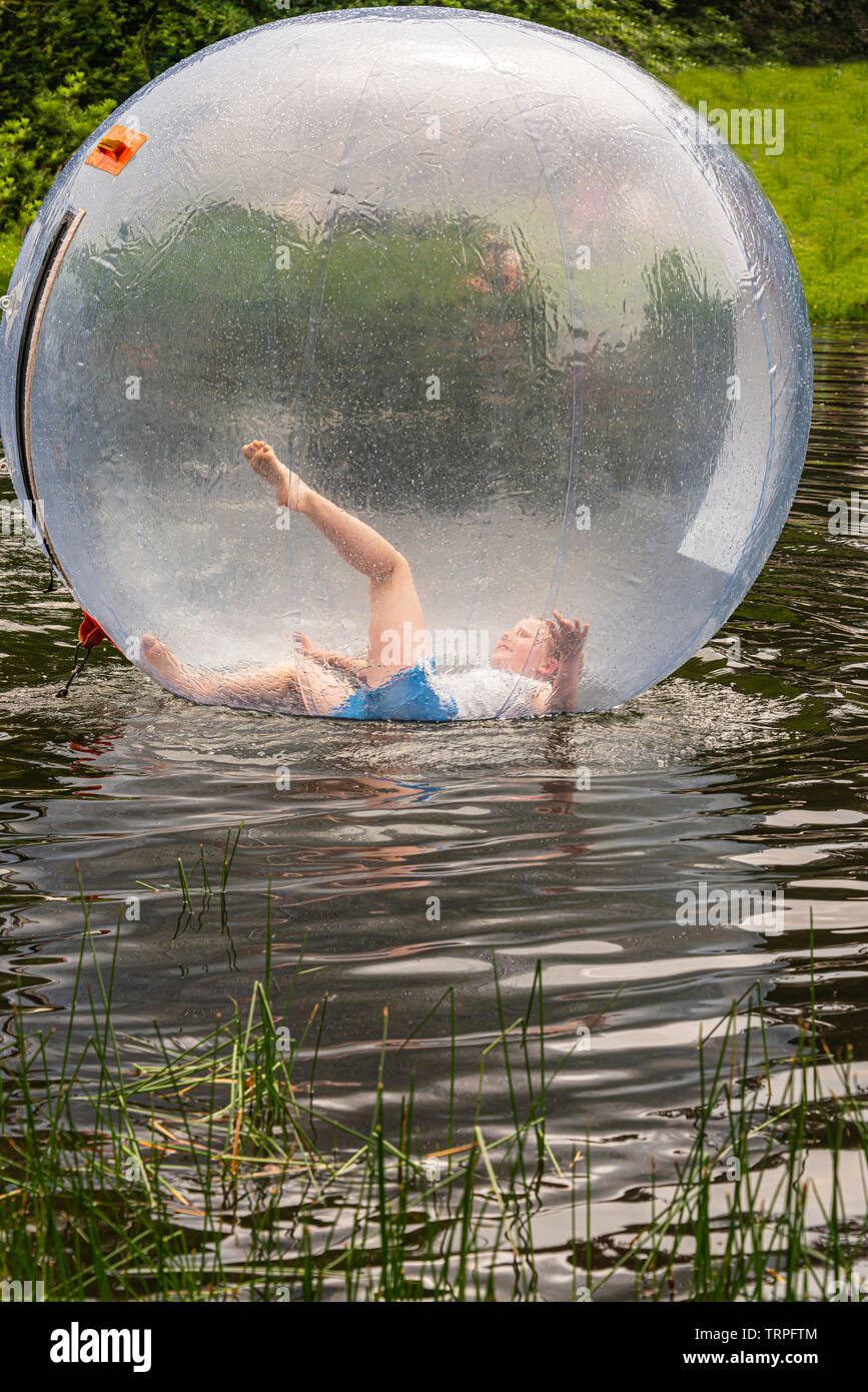 Mädchen mit ihrem linken Bein in einem durchsichtigen aufblasbaren Ballon auf dem Wasser Stockfoto