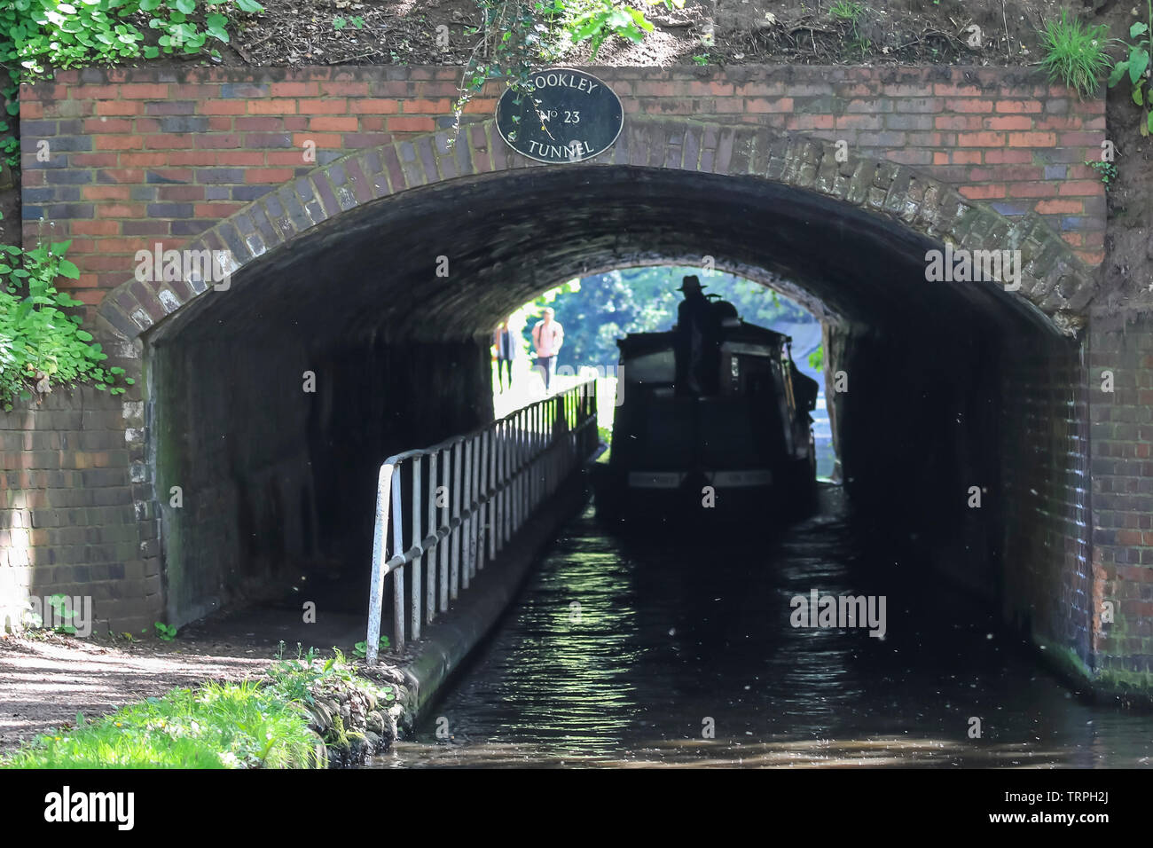Ansicht der Rückseite des Triton mit einem UK canal Weg durch einen dunklen Tunnel Silhouette Kanal; Leute auf leinpfad beobachten, am anderen Ende in hellem Sonnenlicht. Stockfoto