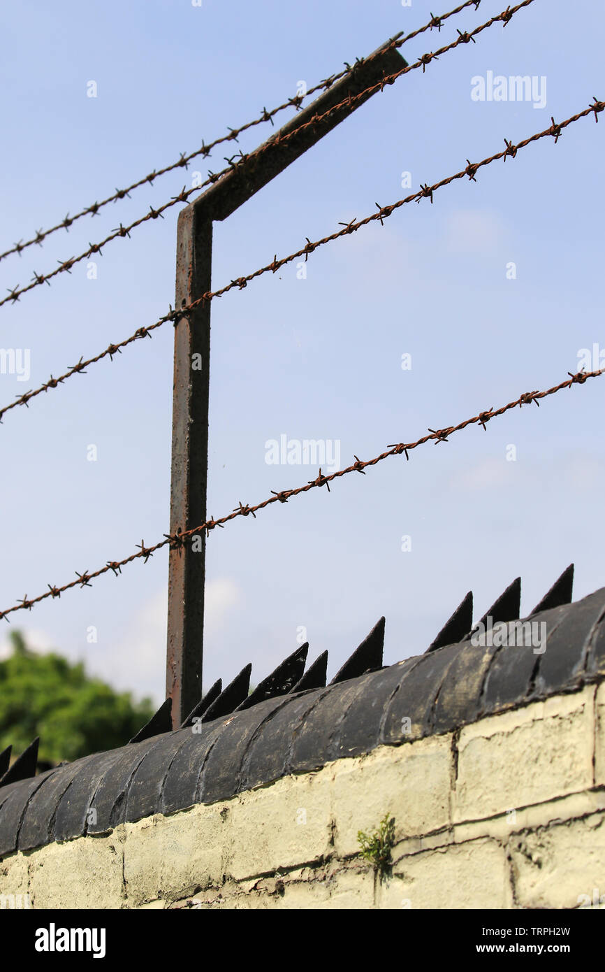 Outdoor hohe Sicherheit, Stacheldrahtzaun, Winkel-Halterung und Rasiermesser Spikes an der Wand: Um unbefugten Zugriff abzuschrecken & für Perimeterschutz. Stockfoto
