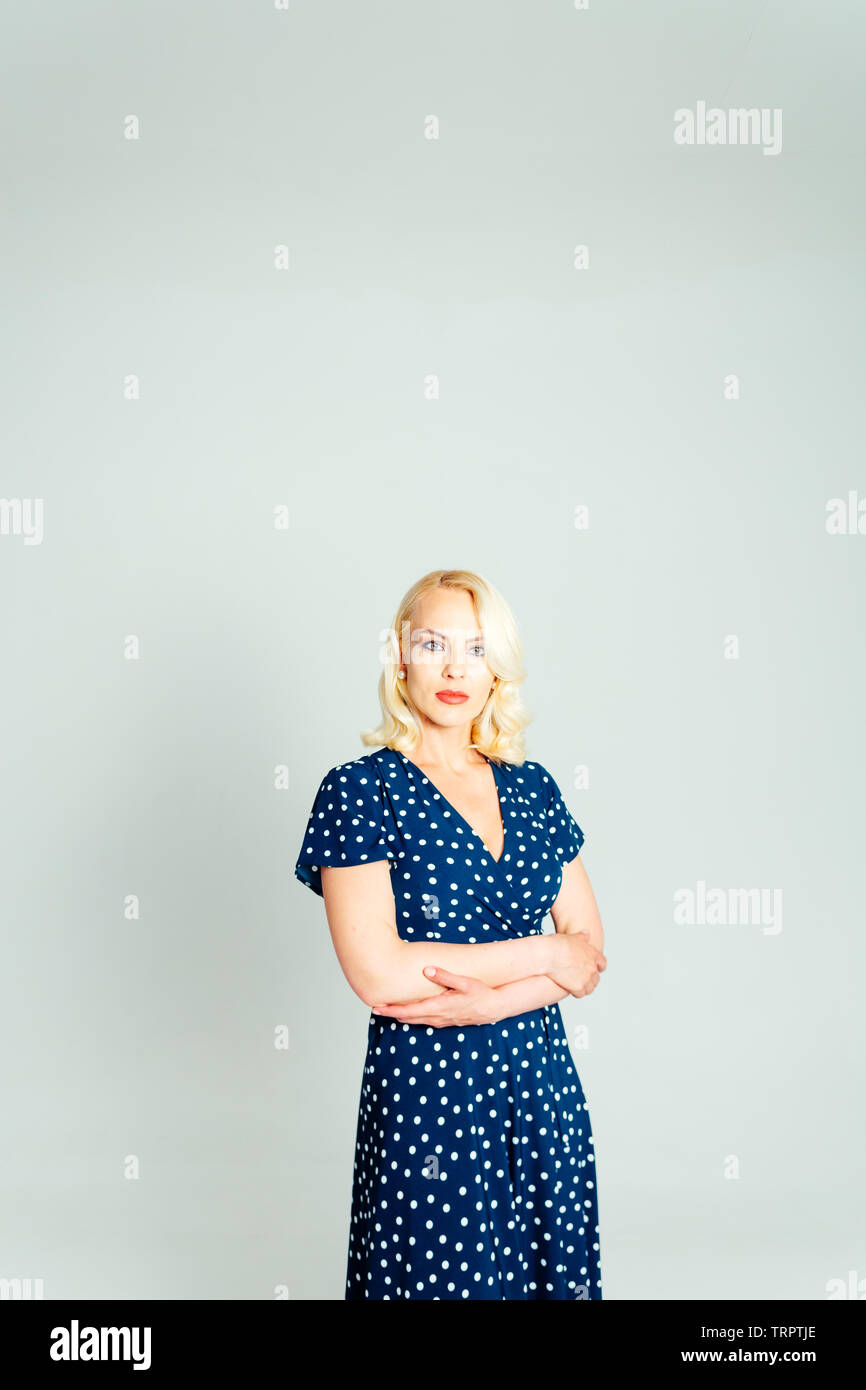 Studio Portrait von schöne blonde Frau in einem dunkelblauen Kleid gegen Weiße einfachen Hintergrund Stockfoto