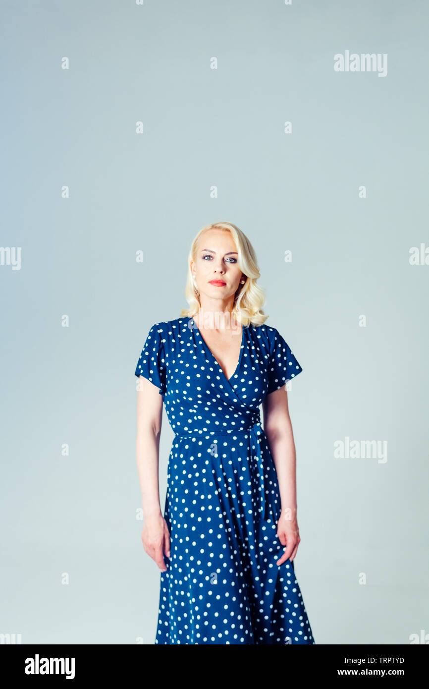 Studio Portrait von schöne blonde Frau in einem dunkelblauen Kleid gegen Weiße einfachen Hintergrund Stockfoto