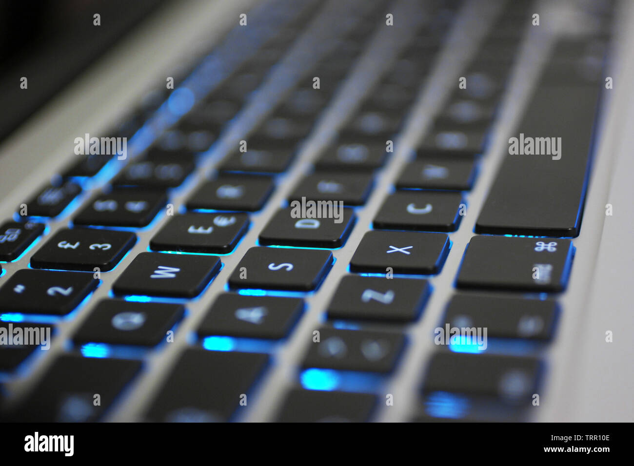 Laptop Tastatur mit blauer Hintergrundbeleuchtung. Tasten closeup zu schwarzen, weissen Buchstaben und Silber Körper. Stockfoto