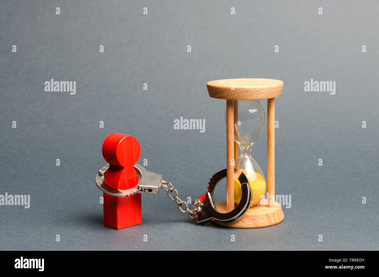 Die rote Figur eines Menschen ist in eine Sanduhr, mit Handschellen gefesselt. Abhängigkeit, gibt es wenig Zeit bleibt. Business zu optimieren, die Effizienz zu erhöhen und die Ausfallzeiten Stockfoto