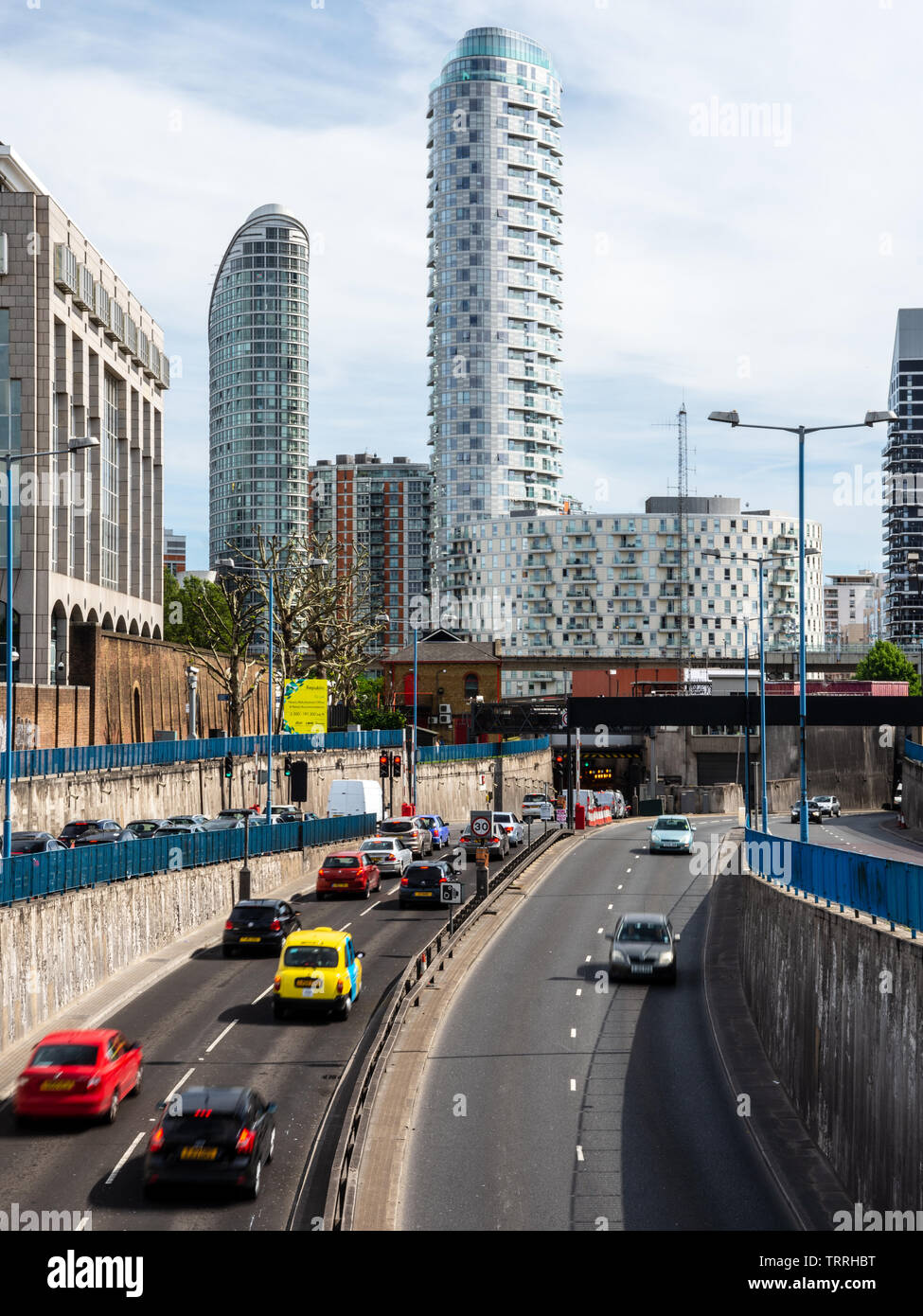 London, England, Großbritannien - 1. Juni 2019: Verkehr auf den Blackwall Tunnel Ansatz Straße unter neuen Build high rise apartment Gebäude in den Docklands Stockfoto
