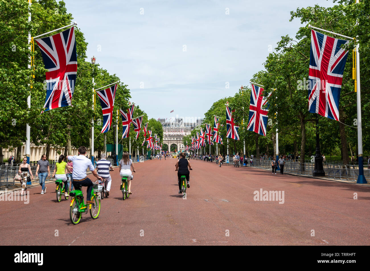 London, England, UK - Juni 1, 2019: Touristen fahren elektrische Fahrräder entlang der Mall in Central London, mit Union Jack Fahnen fliegen. Stockfoto