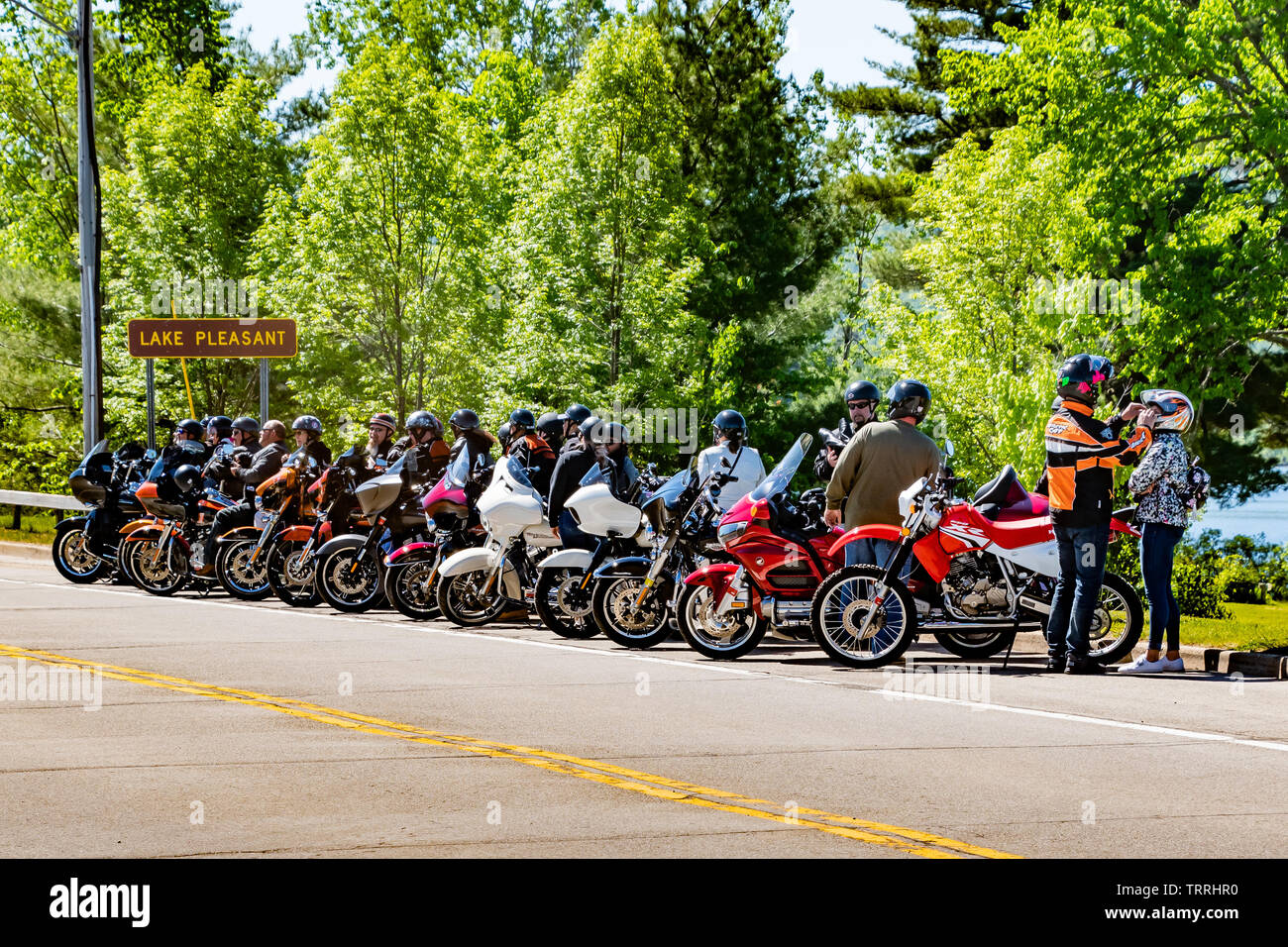 Eine große Gruppe von Motorräder und Fahrer auf der Straße am See angenehm geparkt in den Adirondack Mountains auf einer Tour während Americade 2019. Stockfoto
