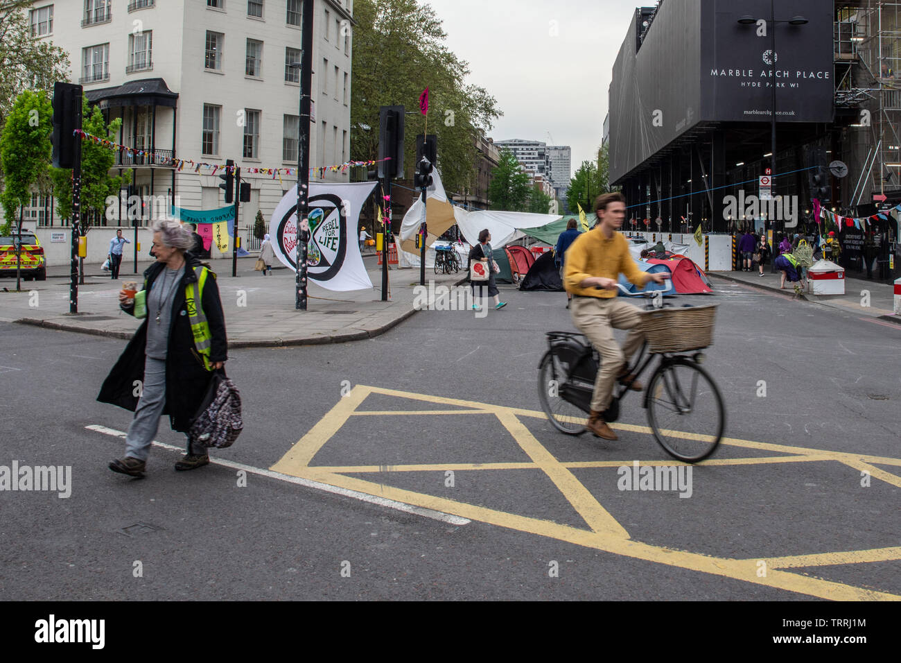 London, England, Großbritannien - 23 April, 2019: ein Radfahrer fährt hinter einem Protest Camp vom Aussterben Rebellion bei Marble Arch in London. Stockfoto