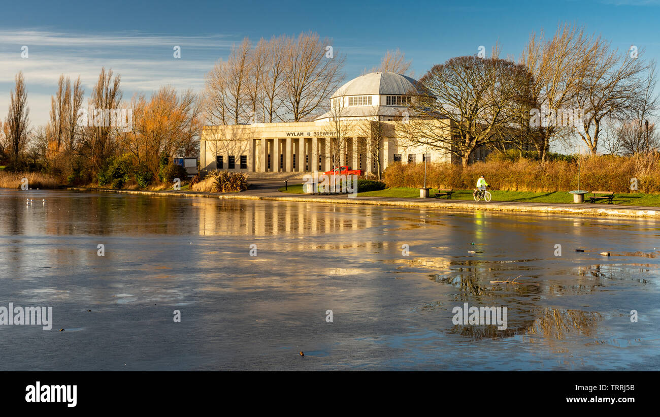 Newcastle, England, Großbritannien - Februar 6, 2019: ein Radfahrer fährt hinter der Art déco-Palast der Künste Gebäude und gefrorenen See an einem Wintertag in der Ausstellung Par Stockfoto