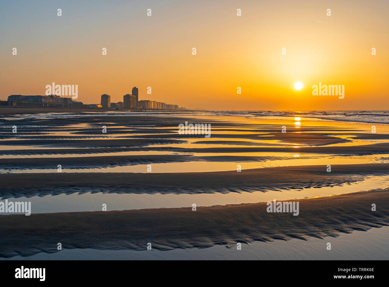 Der Strand von Oostende Stadt bei Sonnenuntergang mit unscharfen Vordergrund durch die Nordsee mit dem städtischen Skyline von Meerblick Apartments, Westflandern, Belgien. Stockfoto