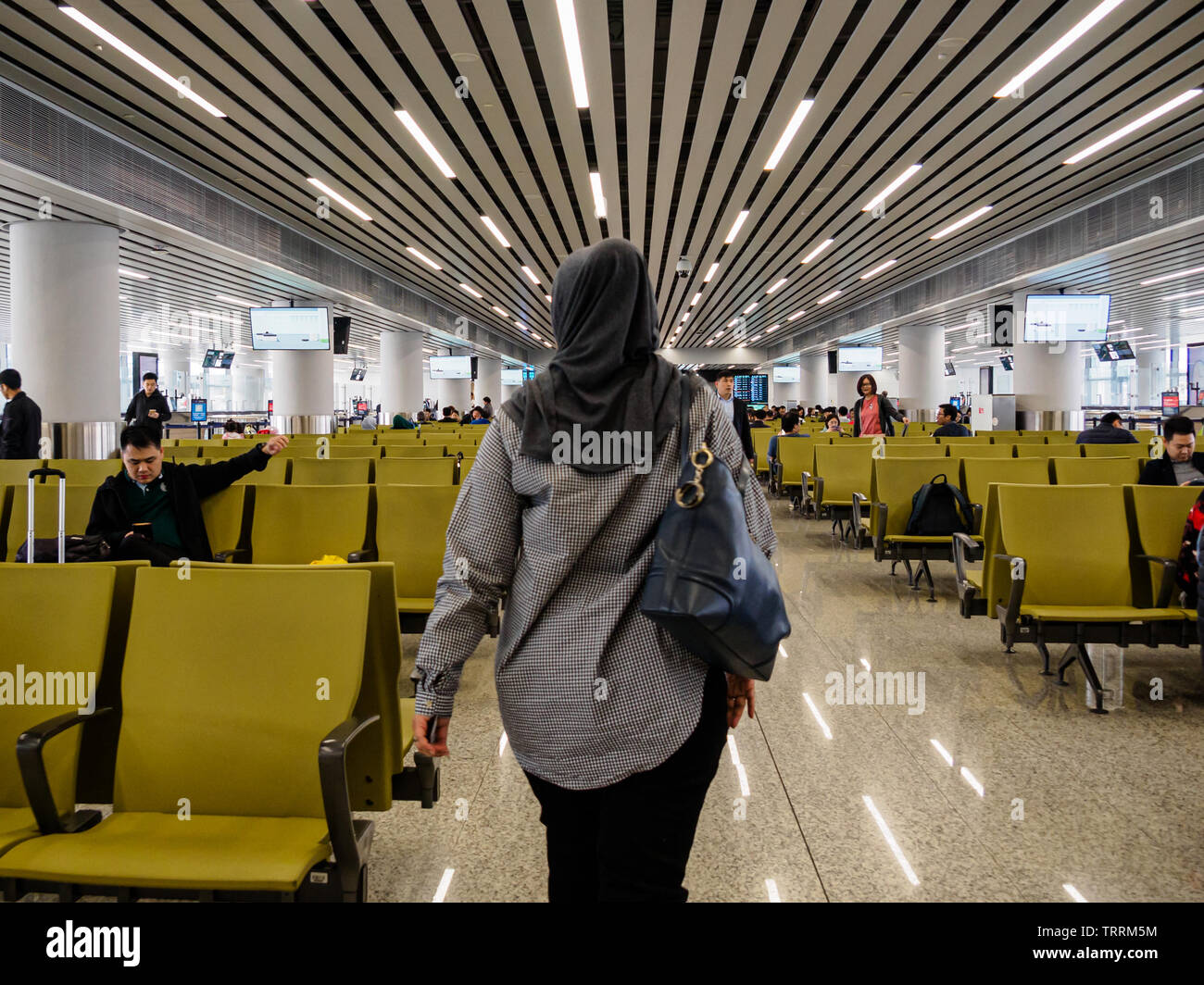 BAIYUN, GUANGZHOU, China - 10 MAR 2019 - Rückansicht einer muslimischen Frau im hijab/Kopftuch geht zu Ihrem Gate am Flughafen Baiyun. China hat eine si Stockfoto