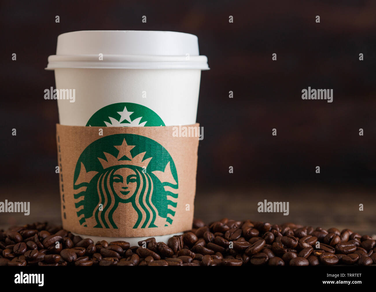LONDON, UK - Juni 05, 2019: Starbucks Kaffee Pappbecher für nehmen Sie mit Kaffeebohnen auf Holz- Hintergrund. Stockfoto