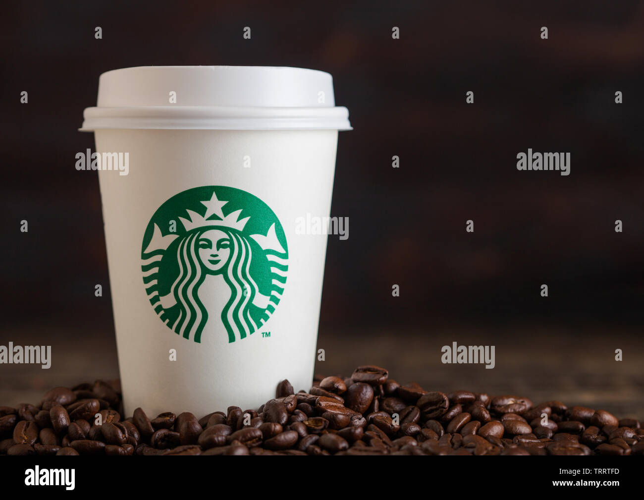 LONDON, UK - Juni 05, 2019: Starbucks Kaffee Pappbecher für nehmen Sie mit Kaffeebohnen auf Holz- Hintergrund. Stockfoto