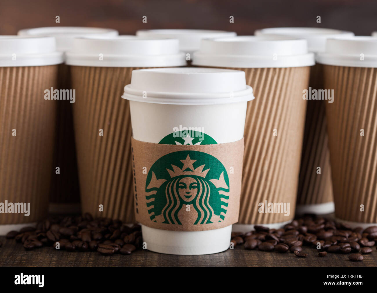 LONDON, UK - Juni 05, 2019: Starbucks Kaffee Pappbecher für nehmen Sie mit Kaffeebohnen auf Holzuntergrund mit leeren braunen Kaffee Tassen. Stockfoto