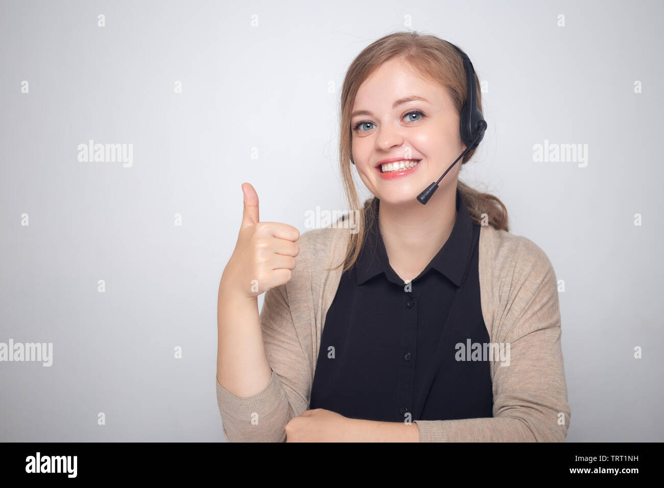 Glücklich lächelnde Junge kaukasier Frau mit Headset Telefon in einem Call Center, Daumen hoch Stockfoto
