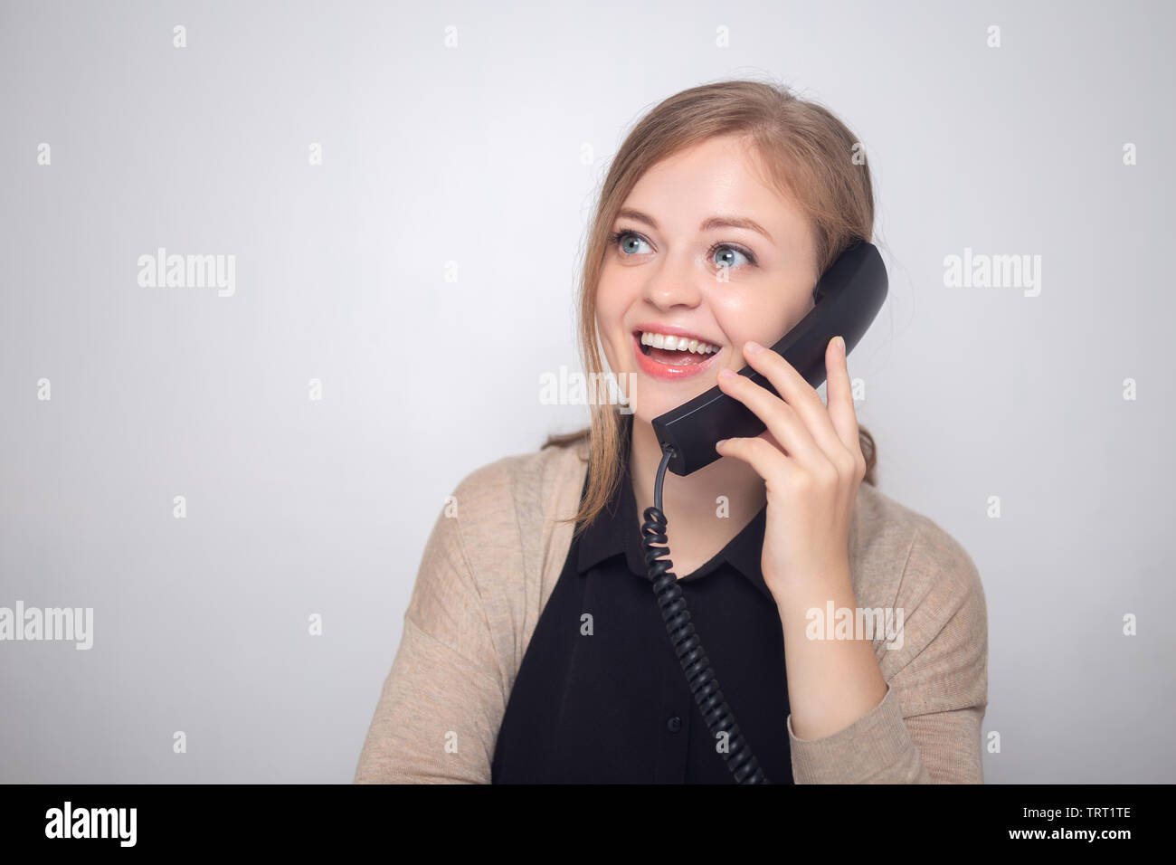 Glücklich lächelnde Junge kaukasier Frau mit Telefon im Call Center oder im Büro Stockfoto