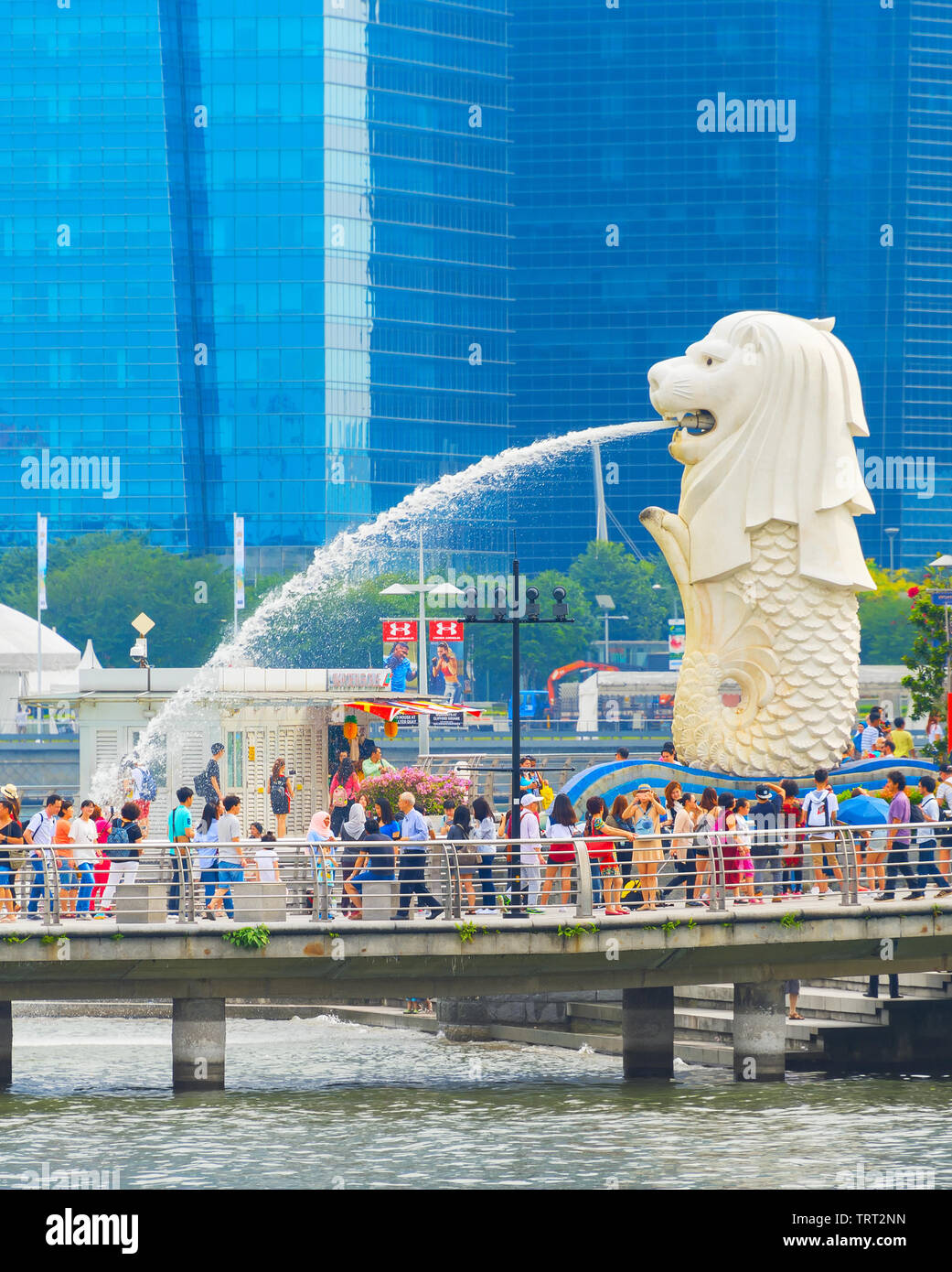 Singapur - Januar 14, 2017: Masse der Touristen durch Singapur Löwenbrunnen und Glasfassaden der Wolkenkratzer im Hintergrund Stockfoto
