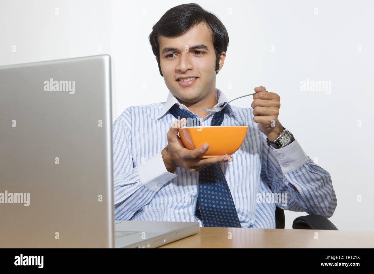 Geschäftsmann, etwas zu essen und mit Blick auf einen laptop Stockfoto