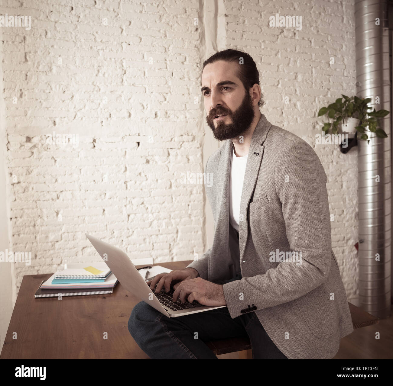 Erfolgreiche hipster Unternehmer Arbeiten am Laptop in seinem modernen Studio Home Office. Suchen glücklich und mit eigenen geschäftlichen Erfolg überzeugt. In Menschen s Stockfoto