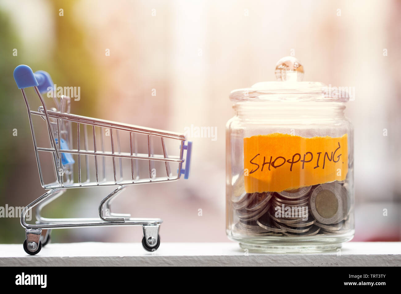 Geld sparen für Shopping Haushalt, Münzen halten im Glas mit Warenkorb Stockfoto