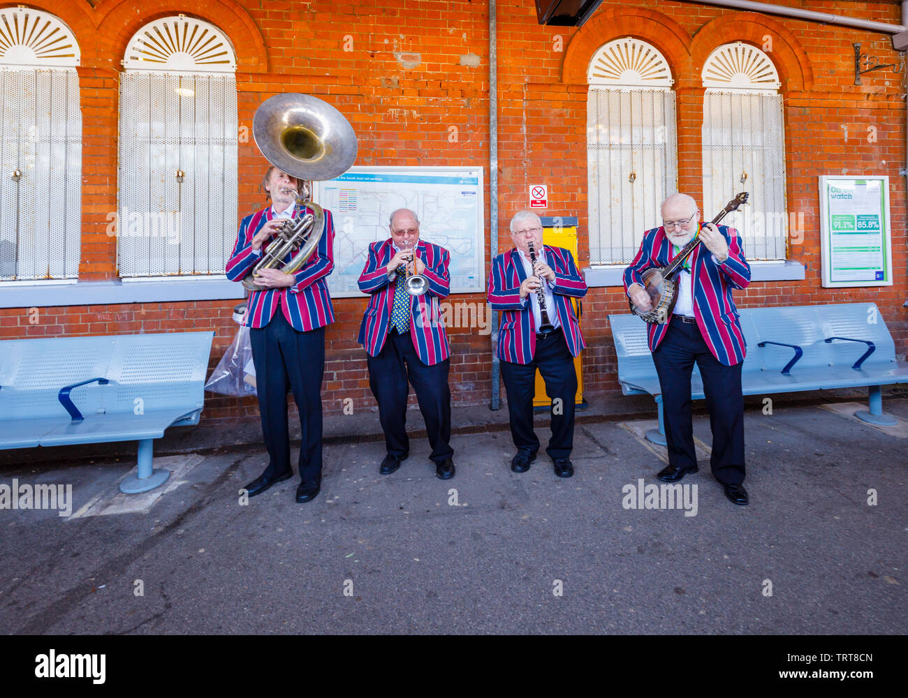 Ältere Musiker aus den Belmond Venice Simplon Orient Express in gestreifter Blazer auf der Plattform in Folkestone West Railway Station durchführen, Kent Stockfoto