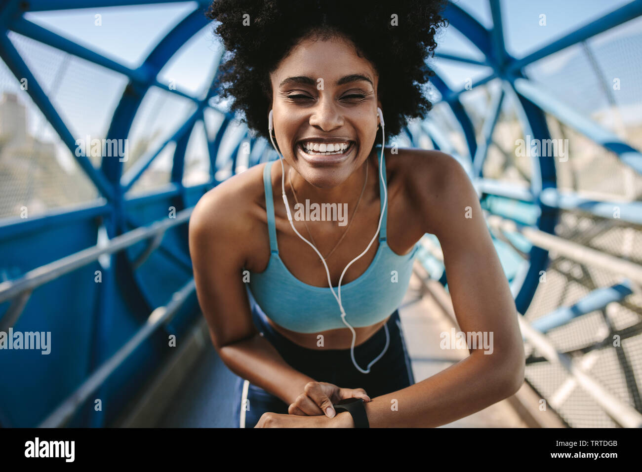 Junge fitness Frau mit smart Watch suchen bei Kamera und lächelnd. Sportlerin einrichten Ihr smart Watch vor einem Lauf. Stockfoto