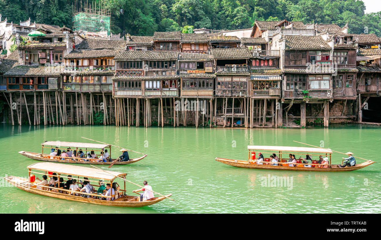 2. Juni 2019, Fenghuang China: traditionelle hölzerne Boote voller Touristen crusing auf Tuojiang Fluss und alten traditionellen Häuser in Riverside in Fenghuan Stockfoto