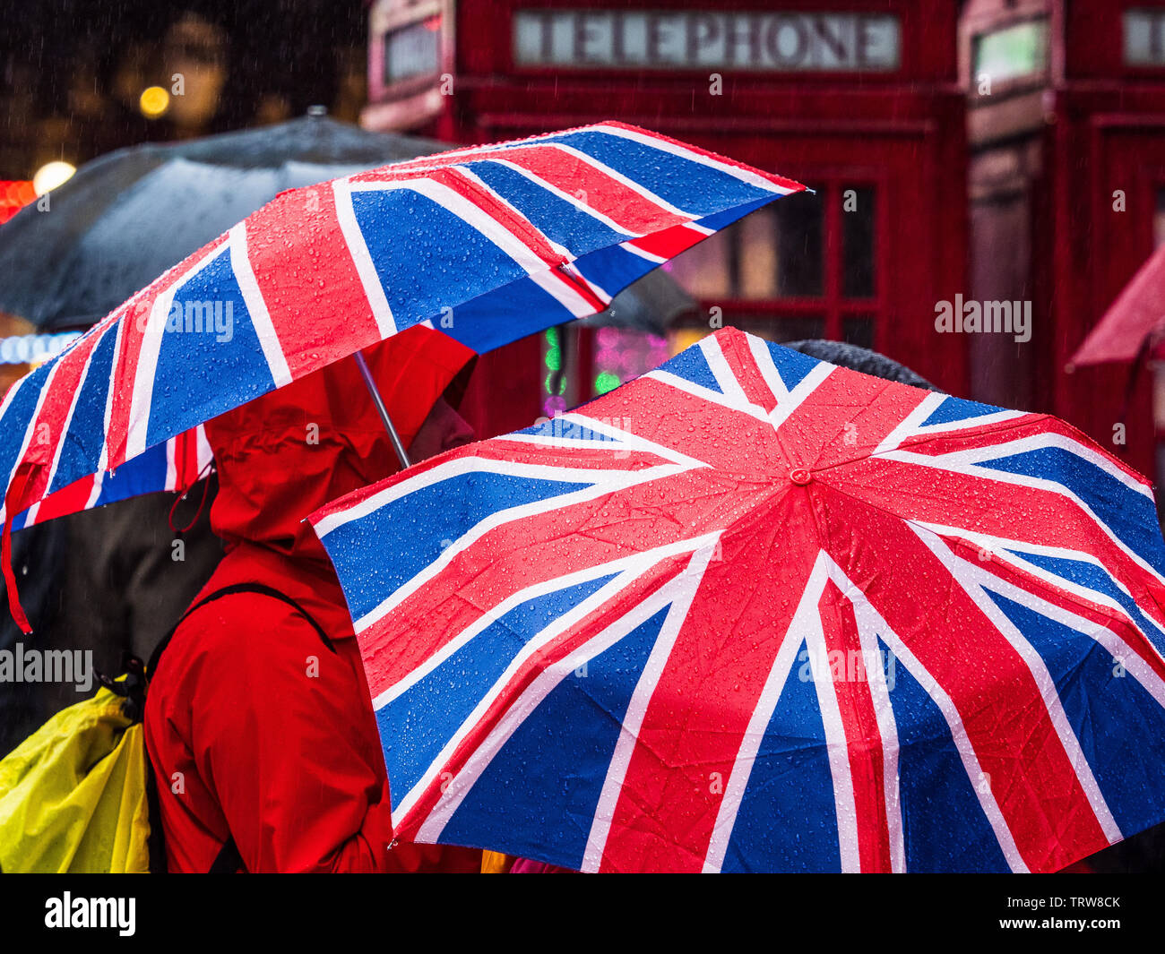 Union Jack schirms im Regen in London. Touristen tragen in Central London Flaggenschirme von Union Jack. Stockfoto