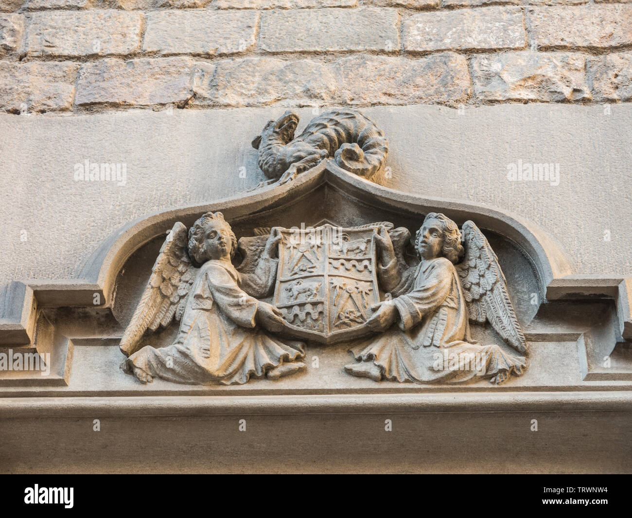 Zwei Engel halten ein altes Schild von Barcelona, der Freimaurerischen Symbole enthält, auf einen Drachen. Tür des Klosters von San Agustín. Barcelona, Spanien. Stockfoto