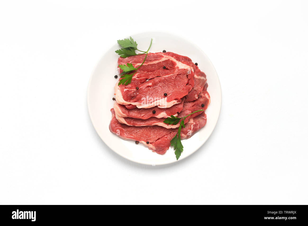Frisches rohes Rindfleisch Steak auf dem Teller auf weißem Hintergrund, Ansicht von oben Stockfoto
