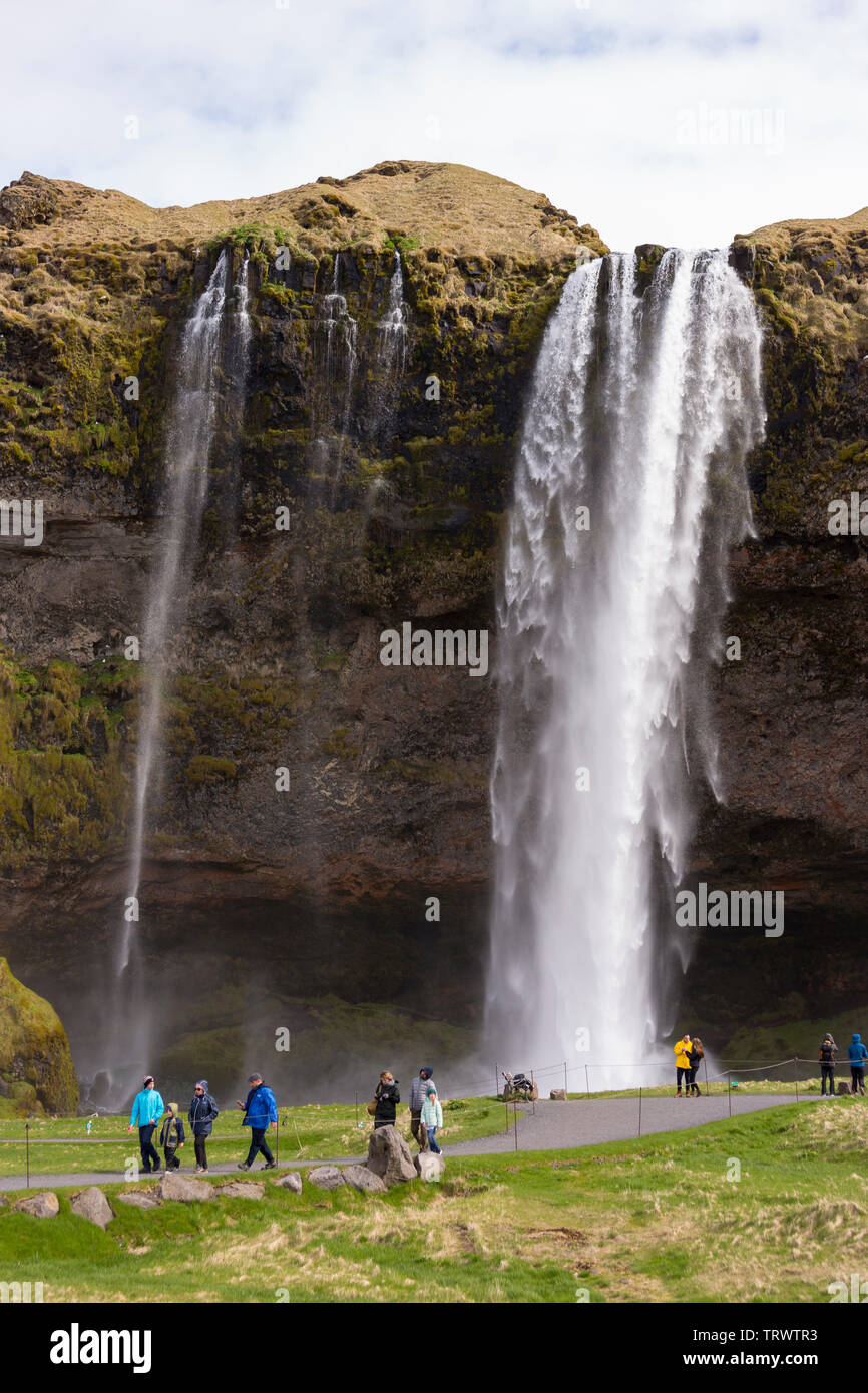 SELJALANDSFOSS, ISLAND - Touristen am Wasserfall auf der südlichen Küste, auf Seljalands River. Stockfoto