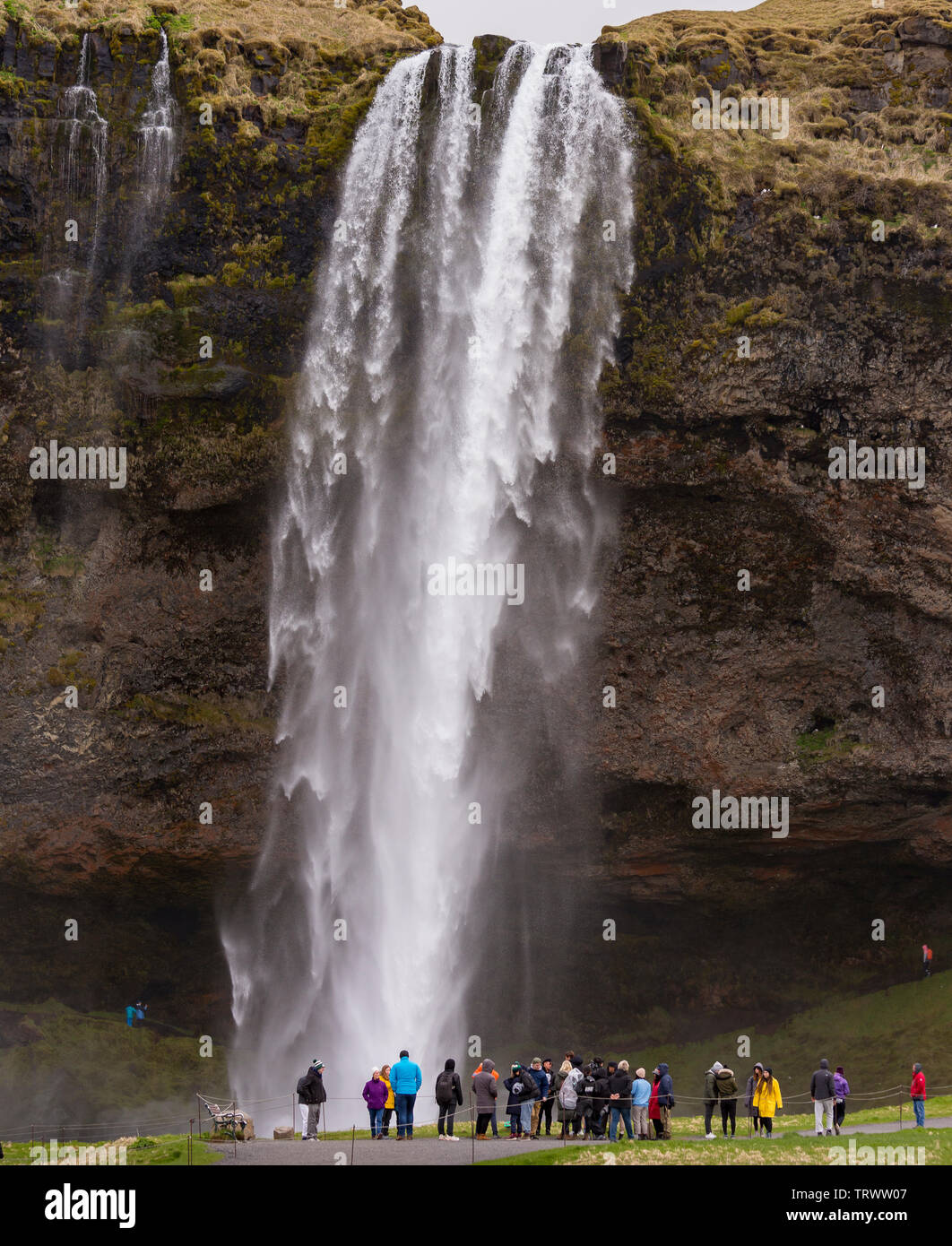 SELJALANDSFOSS, ISLAND - Touristen am Wasserfall auf der südlichen Küste, auf Seljalands River. Stockfoto