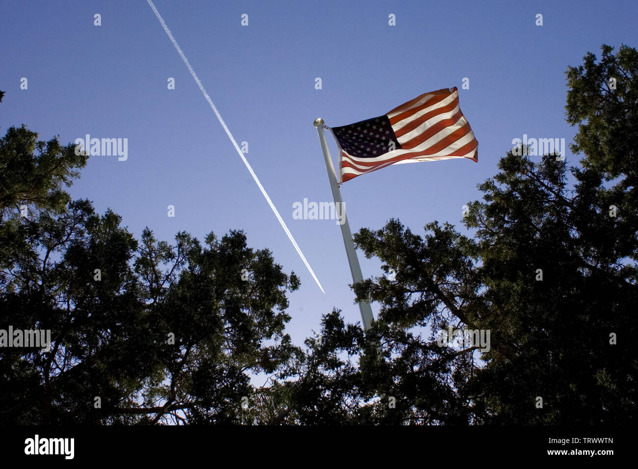 Eine amerikanische Flagge weht im Wind, während ich plane einen Kondensstreifen am Himmel. Stockfoto