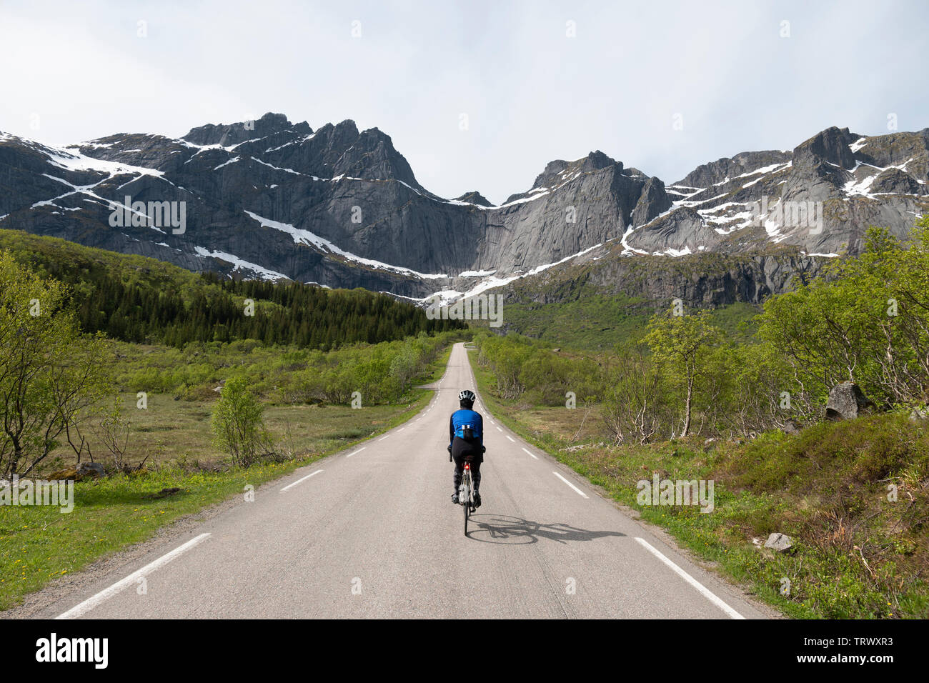 Weibliche Radfahrer auf der Straße nach Nusfjord, Lofoten, Norwegen. Stockfoto