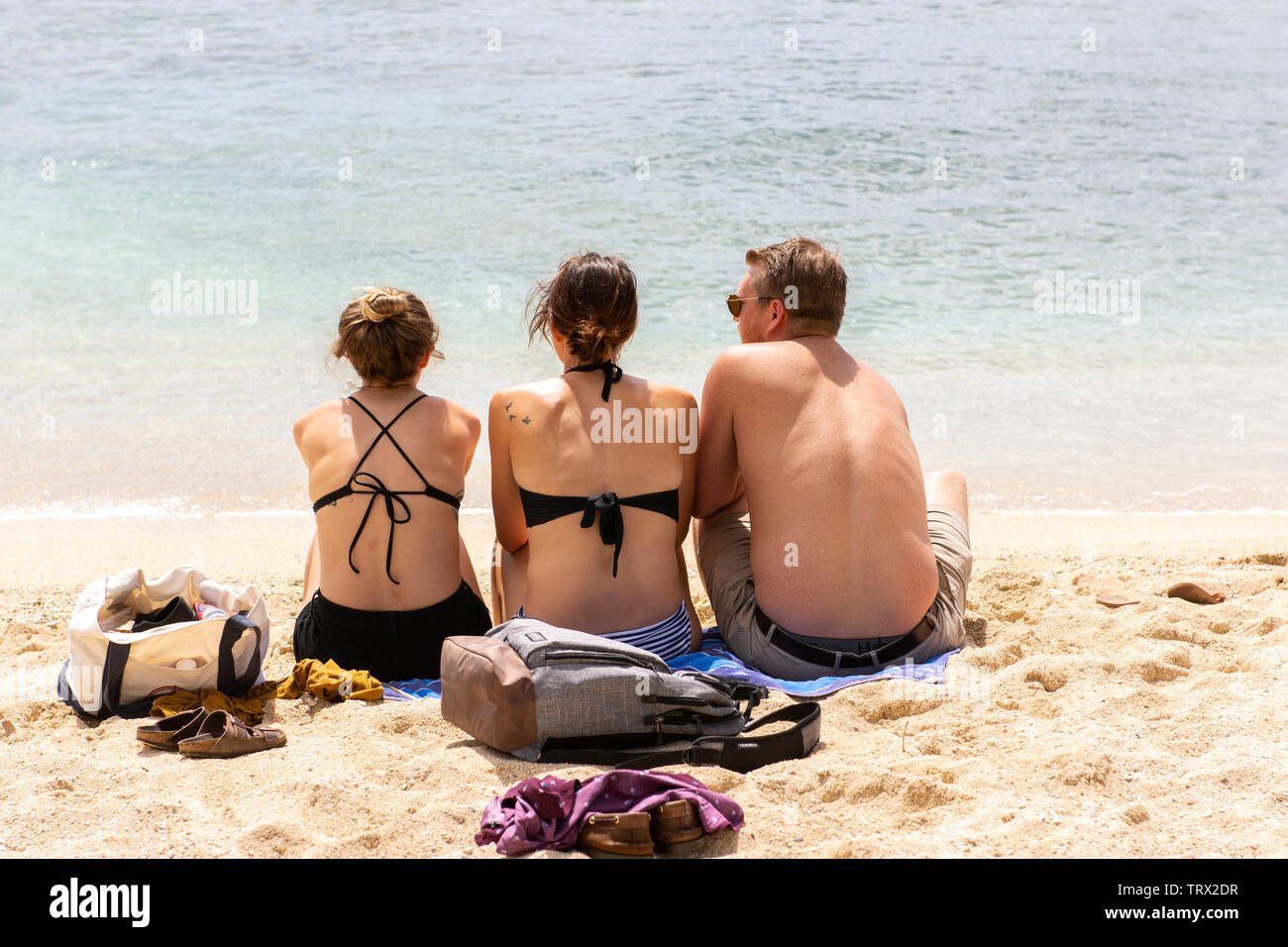 Eine Gruppe von drei Freunden zusammen sitzen am Strand, am Pazifischen Ozean Blick; Waikiki Beach, Honalulu, Hawaii. Stockfoto
