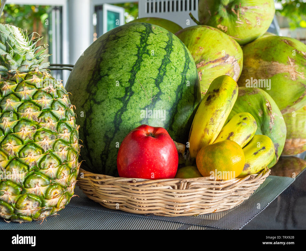 Frische Sommer Obst, Ananas, Wassermelone, roten Apfel, Orangen, Bananen  und Kokosnüsse im Korb auf den Tisch Stockfotografie - Alamy