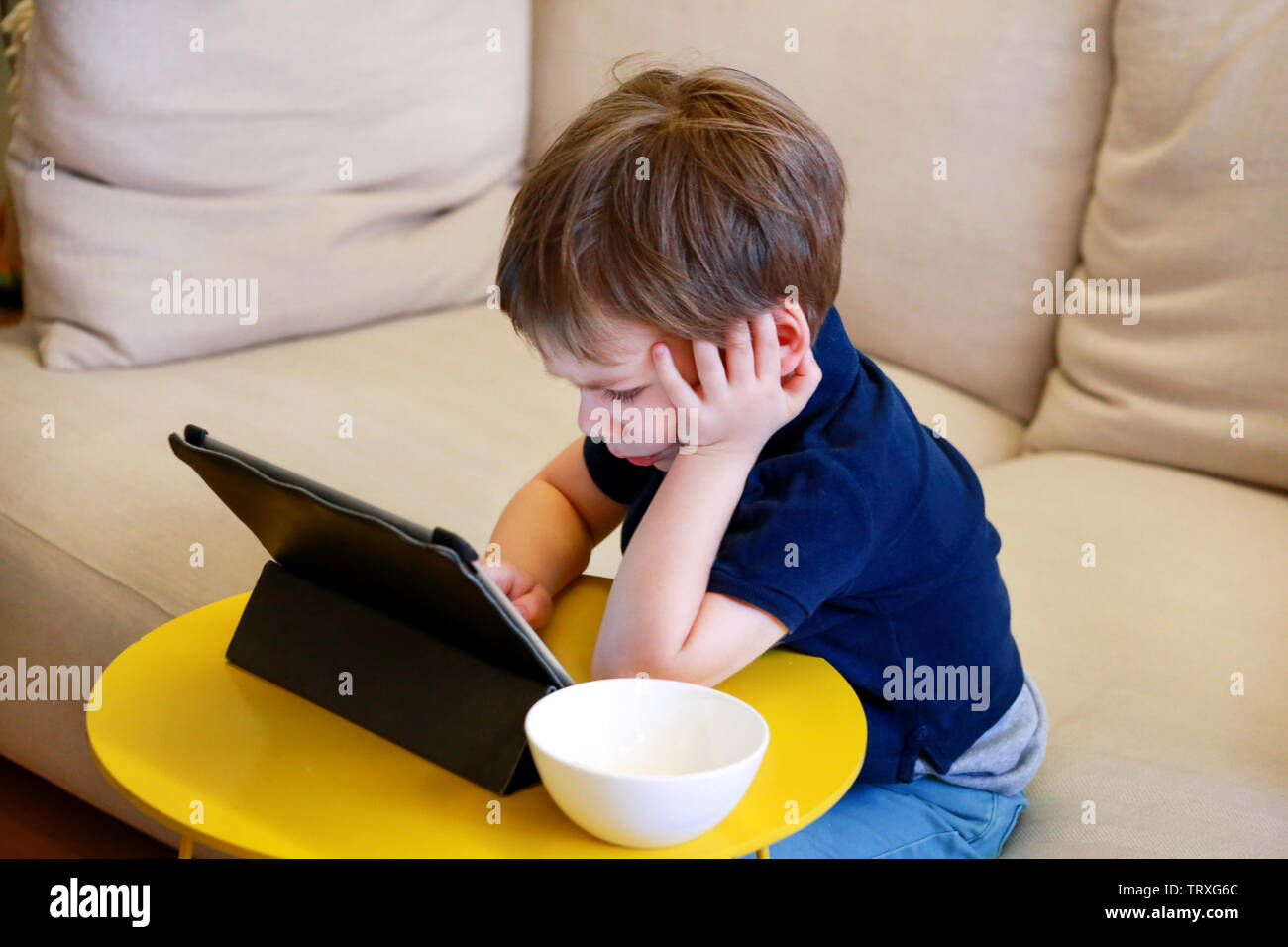 Kind mit Tablet-PC auf Bett zu Hause. Süße junge auf Sofa schaut Cartoons, Spiele spielen und lernen vom Laptop. Bildung, Spaß, Freizeit, das Glück. Stockfoto