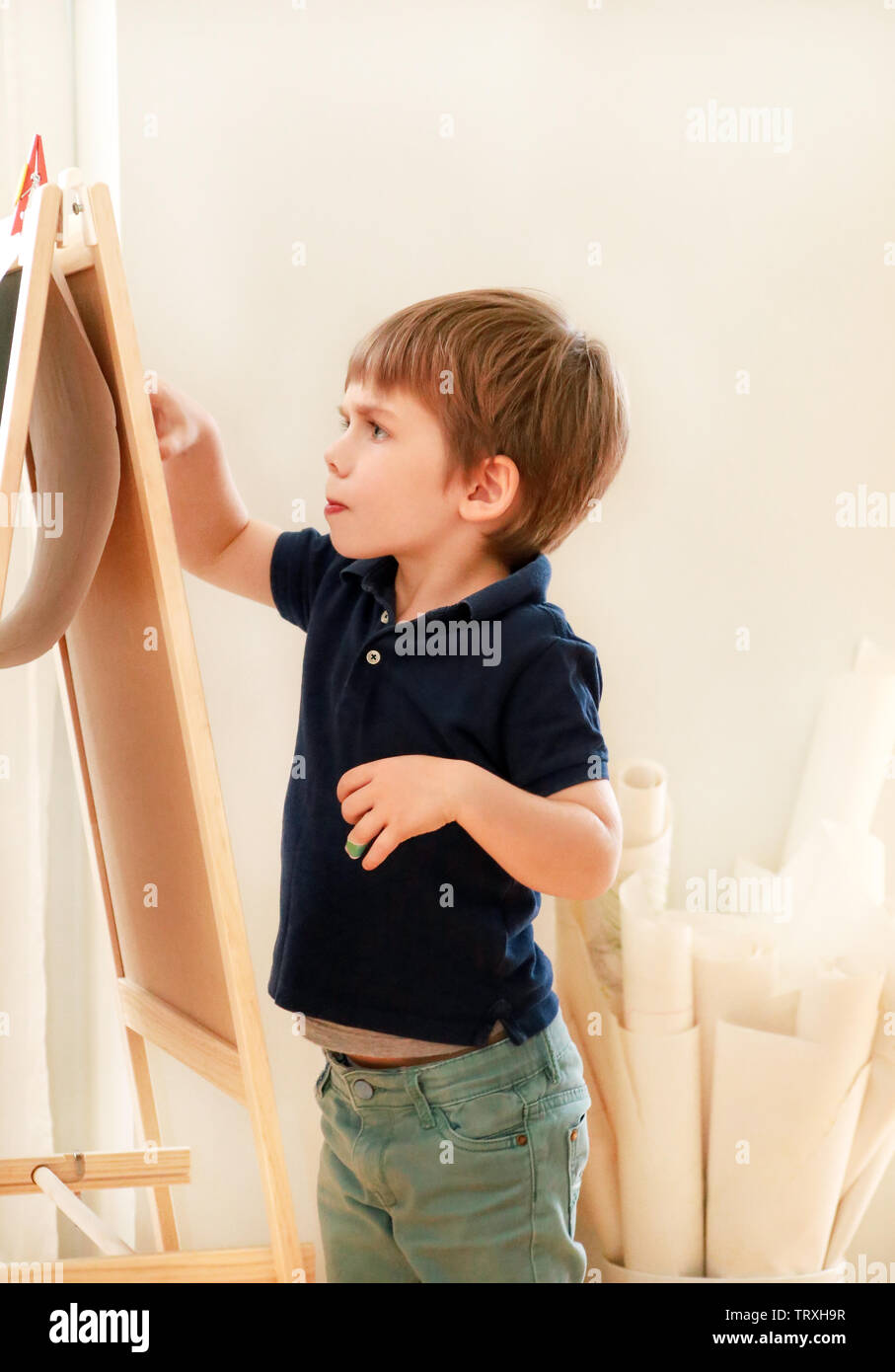 Kind ist das Zeichnen und Malen mit Filzstift auf Papier aus Holz Reißbrett Künstler Staffelei für Kinder und Kinder zu Hause. Kindheit. Cute little boy. Stockfoto