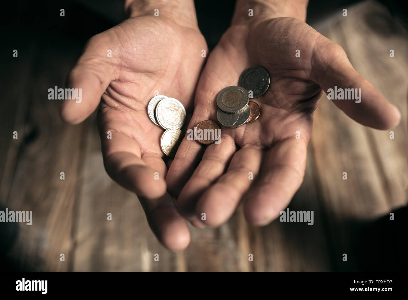 Männliche Bettler Händen Geld, Münzen aus menschlichen Freundlichkeit auf dem Holzboden an öffentlichen Weg oder die Straße Gehweg. Obdachlosen Armen in der Stadt. Probleme mit Finanzen, Wohnort. Stockfoto