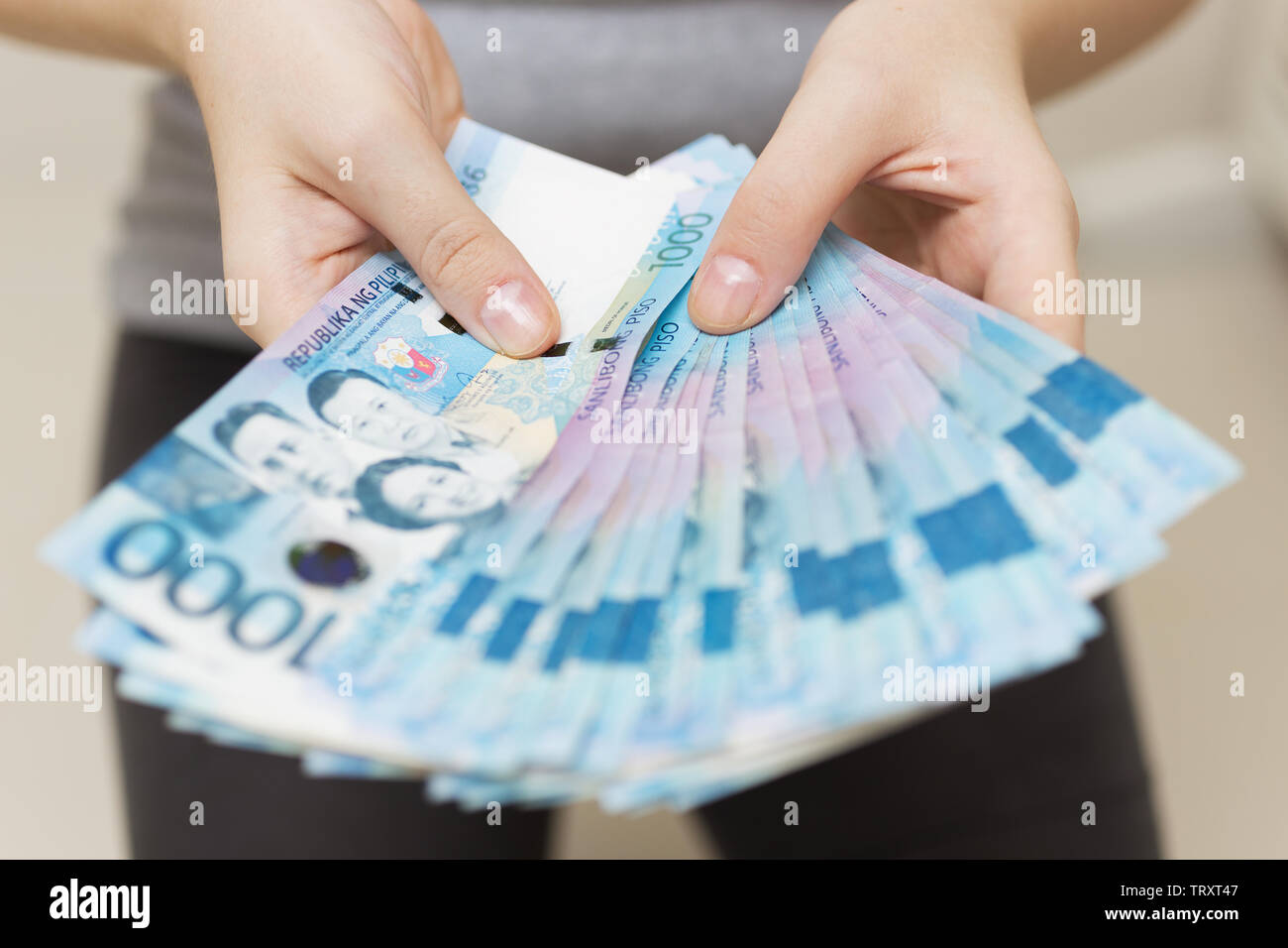Hände halten Gehalt oder Payment Bundle von Bargeld von tausend philippinischen Peso, als wenn sein Reich. Zeigen Sie, Rechnungen bezahlen oder Bestechung geben. Stockfoto