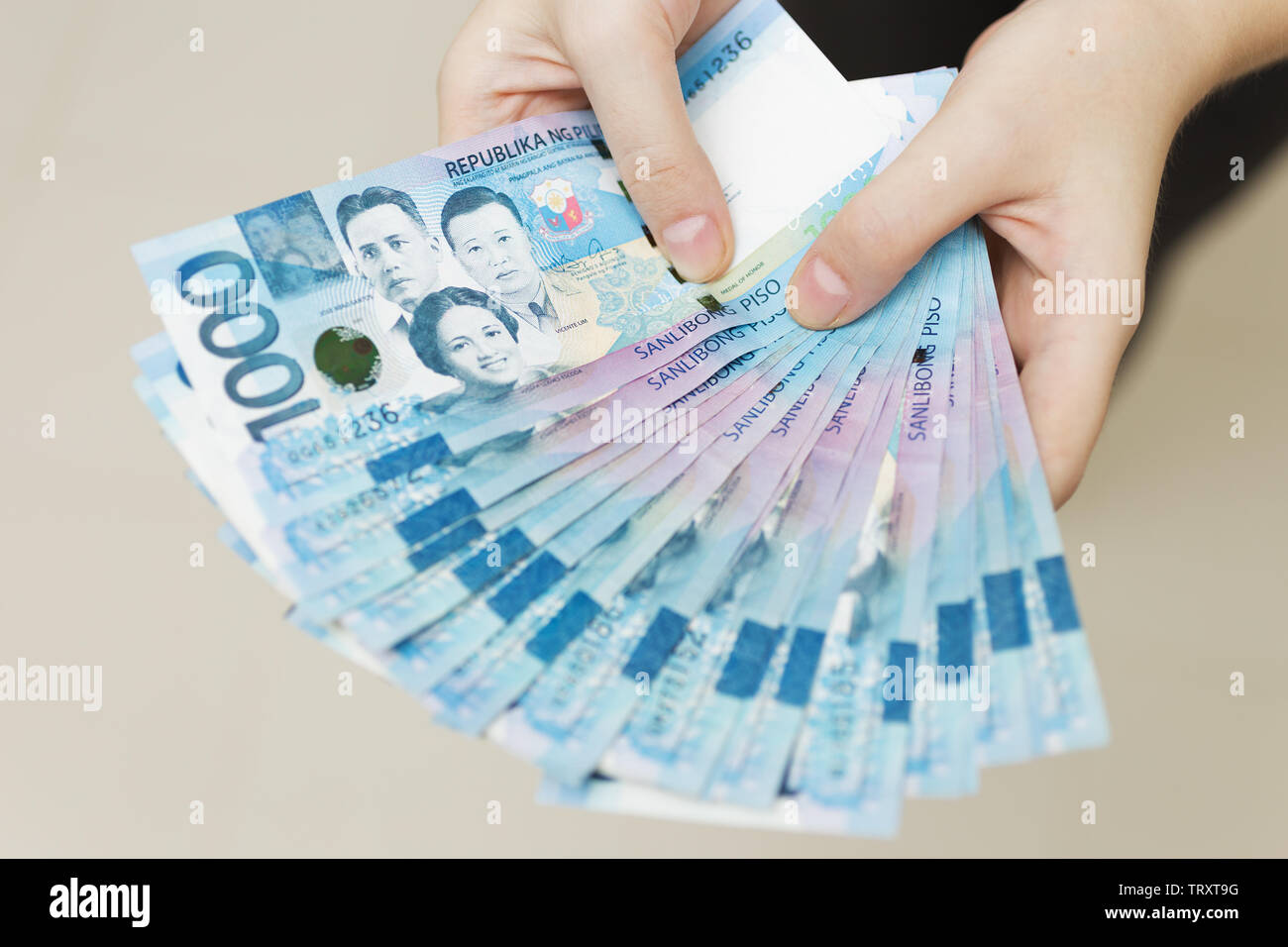 Hände halten Gehalt oder Payment Bundle von Bargeld von tausend philippinischen Peso, als wenn sein Reich. Zeigen Sie, Rechnungen bezahlen oder Bestechung geben. Stockfoto